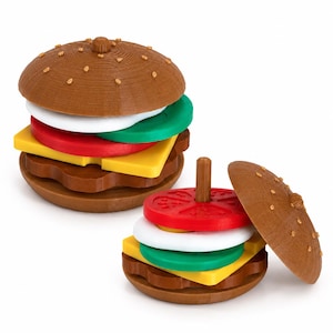 May include: Two wooden toy burgers with brown buns, and colorful layers of white, green, yellow, and red. One burger is assembled, the other is partially disassembled, with a wooden peg in the center.