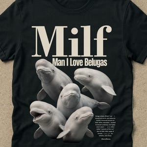Pode incluir: Camiseta preta com o texto "Milf Man I Love Belugas" em negrito e branco. A camiseta apresenta um gráfico de cinco baleias beluga brancas. A palavra "black" está no canto inferior direito.