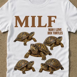 Pode incluir: Camiseta branca com o texto "MILF: Man I Love Box Turtles" em castanho. A camisa apresenta cinco ilustrações de tartarugas-caixa. A palavra "white" está impressa no canto inferior direito.