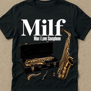 Op de afbeelding: Een zwart t-shirt met de witte tekst "Milf" boven "Man I Love Saxophone". De afbeelding bevat een gouden saxofoon die rechtop staat, een saxofoon in een open zwarte koffer, een losse nek en een mondstuk.