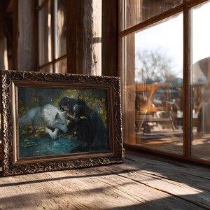 May include: A framed painting depicting a woman in a dark dress interacting with a white wolf. The artwork is set in a naturalistic environment with flowers and water. The frame is ornate with a gold finish, resting on a wooden surface.
