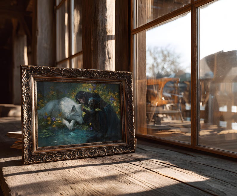 May include: A framed painting depicting a woman in a dark dress interacting with a white wolf. The artwork is set in a naturalistic environment with flowers and water. The frame is ornate with a gold finish, resting on a wooden surface.