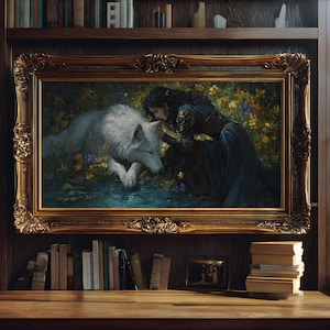 May include: A framed painting depicts a woman in a dark blue dress interacting with a white wolf in a floral setting. The ornate gold frame surrounds the artwork, displayed on a wooden surface with books and a window in the background.