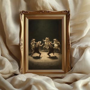 May include: A framed print featuring a whimsical scene of five anthropomorphic frogs dancing in a circle. The artwork is set against a dark background and framed in a gold ornate frame. The print is displayed on a cream-colored fabric.