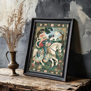 May include: Framed tapestry art featuring a medieval knight on horseback in a colorful landscape. The artwork is framed in a black wooden frame and is leaning against a textured wall. A vase with dried plants is in the foreground.