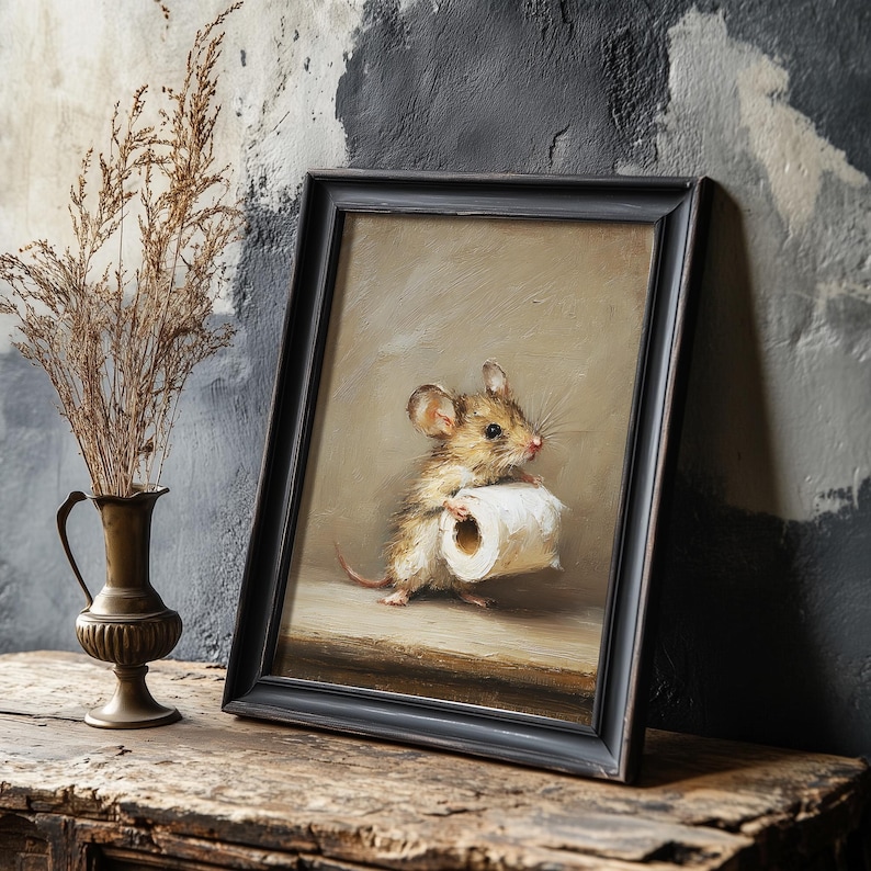 May include: A framed oil painting depicting a small brown mouse standing on a wooden surface while holding a roll of white toilet paper. The artwork is enclosed in a simple black frame, showcasing a neutral beige background and detailed brushwork.