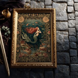 May include: A framed artwork featuring a mermaid with flowing red hair in an underwater scene. The artwork is in a gold frame with ornate detailing. A sword and decorative items are next to the framed artwork.