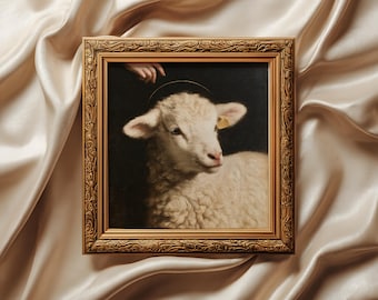 May include: A square painting in an ornate gold frame depicting a white lamb with a thin halo above its head against a dark background. A human hand is visible at the top edge, and the lamb has a small yellow tag on its left ear.
