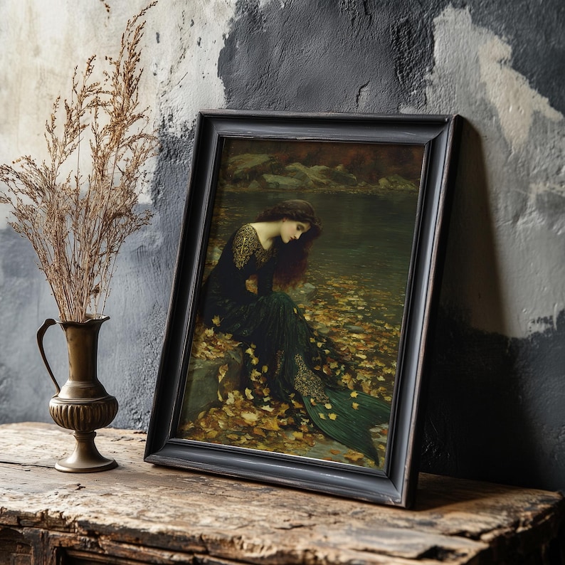 May include: A framed print of a Pre-Raphaelite painting. The artwork depicts a woman in a dark green dress with gold accents, seated near a body of water. The frame is black, and the overall aesthetic is vintage.