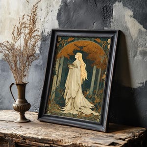 Op de afbeelding: Ingelijste kunstdruk met een vrouw in een witte jurk, die een kom vasthoudt, tegen een bosachtergrond met goud- en groentinten. Het kunstwerk zit in een zwarte lijst en leunt tegen een getextureerde muur.