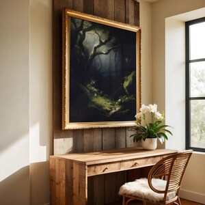 May include: A framed landscape painting with a gold ornate frame hangs above a wooden desk. The painting depicts a dark forest scene with a path leading into the distance. A white orchid plant sits on the desk near a window.