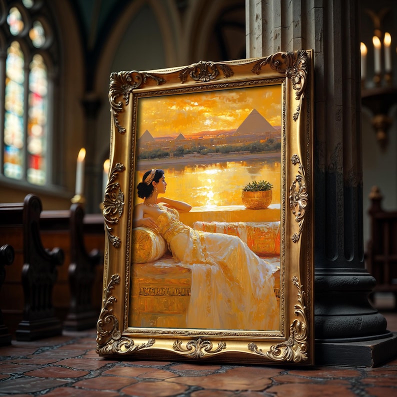 May include: A framed painting depicting a woman in a white gown sitting on a stone ledge overlooking a river and pyramids in the distance. The sky is a vibrant orange and yellow, creating a warm and inviting atmosphere.