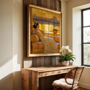 May include: A framed painting of a woman in a white gown sitting on a couch with a view of pyramids in the background. The painting is hanging on a wooden wall with a desk and chair in front of it.
