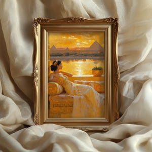 May include: A framed painting depicting a woman in a white gown sitting on a golden couch, looking out at a sunset over a body of water with pyramids in the background.