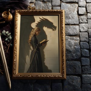 May include: A framed artwork with a gold ornate frame depicts a woman in a black dress reading a book, with a dragon shadow behind her. A sword, roses, and a decorative item are next to the frame. The artwork has a fantasy theme.