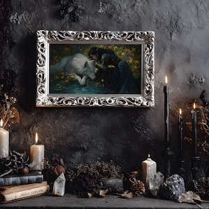 May include: A framed artwork with a silver ornate frame depicts a woman and a white wolf. The scene is set against a dark background, with lit candles, books, and crystals. The overall aesthetic is gothic and mystical.