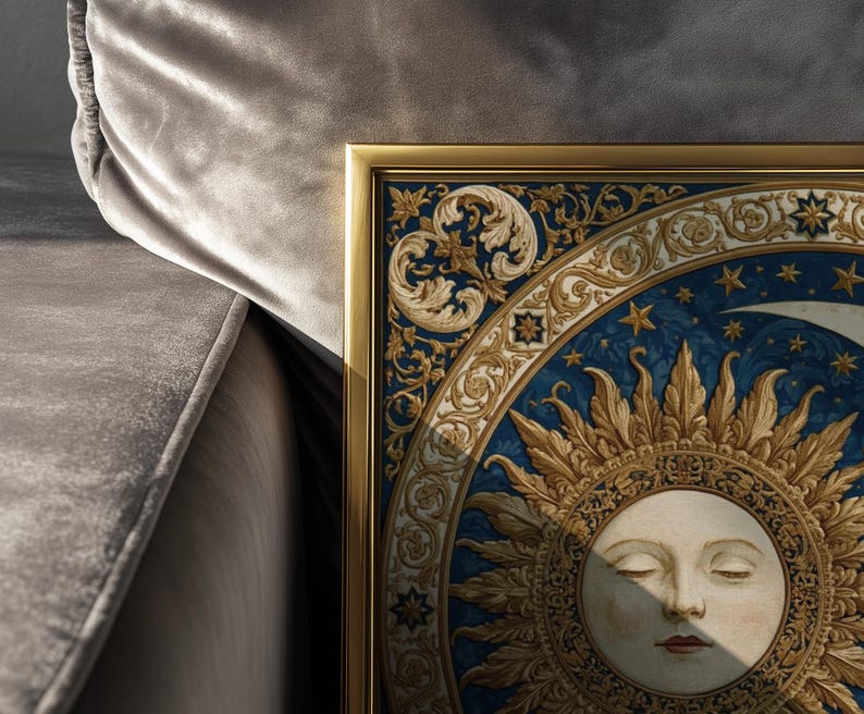 May include: A framed wall art print featuring a central sun face with closed eyes, surrounded by intricate gold and blue decorative scrollwork, star motifs, and a crescent moon, all encased in a thin, metallic gold-colored rectangular frame.