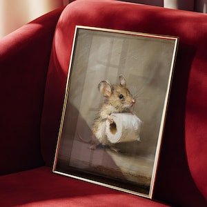 May include: A framed rectangular wall art print featuring an oil painting of a small brown mouse holding a white roll of toilet paper. The mouse has large ears, whiskers, and a light-colored belly. The artwork is encased in a thin gold metal frame.