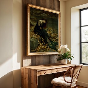 May include: A framed painting with a gold ornate frame depicts a woman in a dark green dress sitting near water. The painting is mounted on a wooden wall above a wooden desk with a wicker chair.