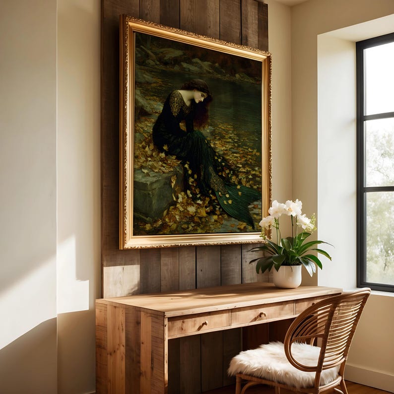 May include: A framed painting with a gold ornate frame depicts a woman in a dark green dress sitting near water. The painting is mounted on a wooden wall above a wooden desk with a wicker chair.