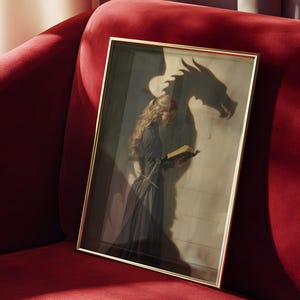 May include: A framed artwork featuring a woman in a dark dress reading a book, with a dragon's shadow cast on the wall behind her. The artwork has a gold frame and is set against a red velvet couch.