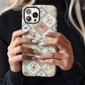May include: A white iPhone case with a colorful pattern of houses, flowers, and checkered squares. The case has a cutout for the camera lens.