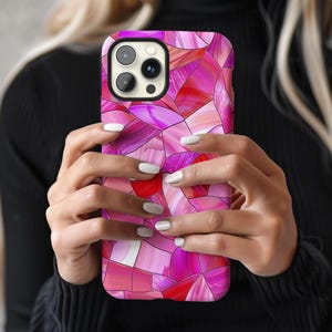 May include: A pink and red geometric patterned phone case for an iPhone.
