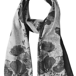 May include: A black and white floral patterned scarf with a black border. The scarf is made of a soft, lightweight fabric and features a delicate floral design.