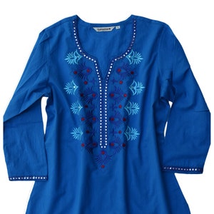 Puede incluir: Una túnica de algodón azul con diseños florales bordados y pedrería. La túnica tiene cuello en V y mangas 3/4.