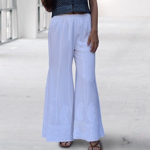 May include: White palazzo pants with white embroidery around the bottom hem.