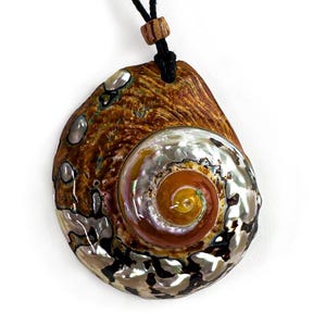 May include: A spiral-shaped pendant crafted from a polished shell featuring iridescent mother-of-pearl accents in shades of silver, green, and brown. The pendant is suspended from a black cord with a small, cylindrical wooden bead above the shell.