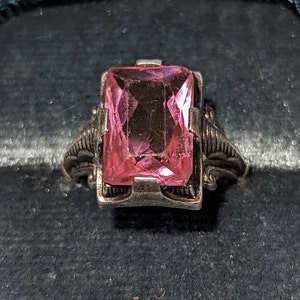 Op de afbeelding: Een zilveren ring met een grote, roze, rechthoekige edelsteen.