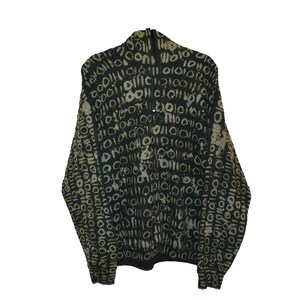 Op de afbeelding: Een donkergroene jas met ritssluiting en een herhalend patroon van witte en beige cirkels. De jas heeft een hoge kraag en een ritssluiting over de hele lengte. De stof lijkt een zacht, geweven materiaal te zijn.