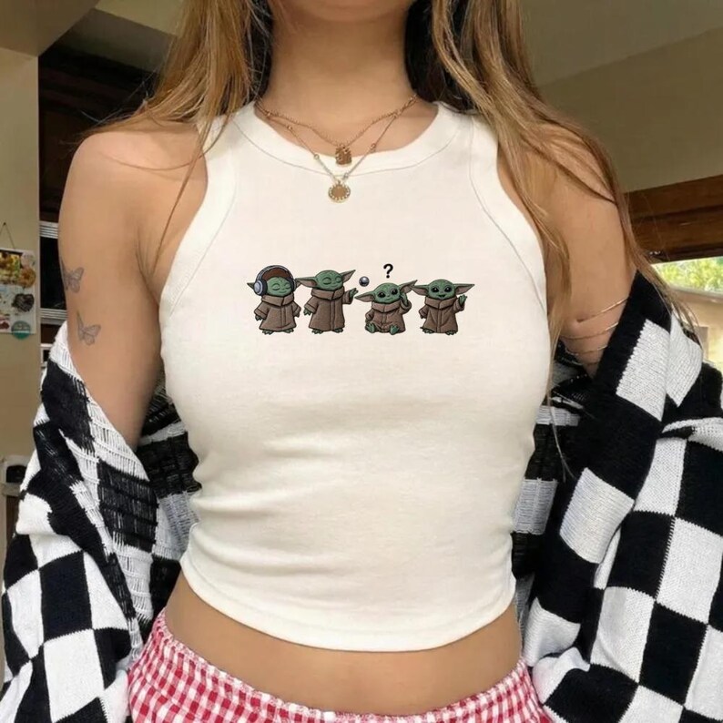May include: White tank top with a graphic of four Grogu characters in brown robes. The first Grogu wears headphones, the second is gesturing, the third has a question mark, and the fourth is smiling.