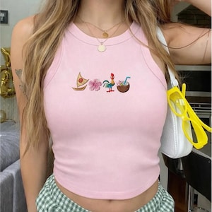 May include: Pink tank top with embroidered tropical designs, including a sailboat, flower, rooster, and coconut drink. The top has a round neckline and is sleeveless. The fabric appears to be a soft, lightweight material.