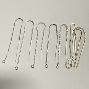 May include: A collection of silver threader earrings in various styles. The earrings feature delicate chains, thin bars, and decorative links. The designs include simple, elegant, and textured options, all with a polished finish.