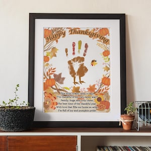 May include: Thanksgiving-themed framed art print with a handprint turkey design. The print includes the text "Happy Thanksgiving" and a poem about gratitude, pumpkins, and family. The artwork is framed in a black frame.