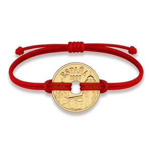May include: A red string bracelet with a gold coin charm featuring a depiction of a building and the text "ESPAÑA 1997".