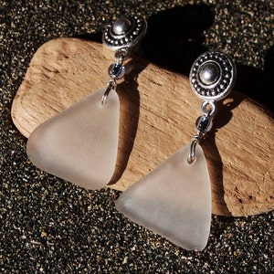 May include: A pair of silver earrings with frosted glass triangle pendants. The earrings feature a silver bead and a silver disc with a decorative pattern.