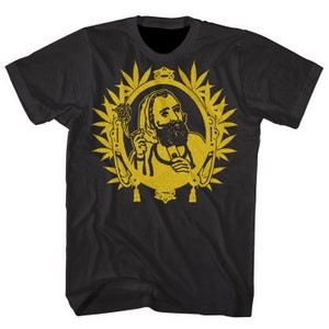 May include: Black t-shirt featuring a gold-colored illustration of a bearded man holding a flower and a smoking device, framed by a decorative border of cannabis leaves. The design is centered on the front of the shirt.