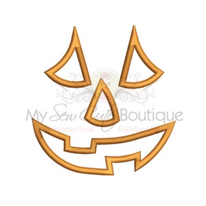May include: A gold outline of a jack-o'-lantern face with a wide smile and two triangular eyes.