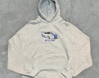 May include: A gray hooded sweatshirt with a white car graphic and the word "SKYLINE" printed in blue on the front.
