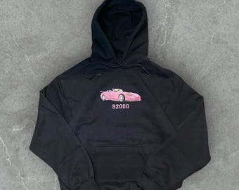 May include: Black hooded sweatshirt with a pink car graphic and the text "S2000" embroidered on the front.