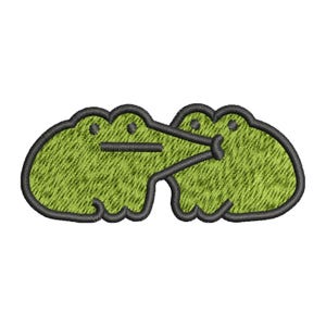 Puede incluir: Parche bordado verde de dos ranas de dibujos animados besándose. Las ranas están delineadas en negro.