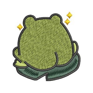 May include: Green embroidered frog with a happy expression, sitting with its legs crossed. The frog is surrounded by small gold stars.