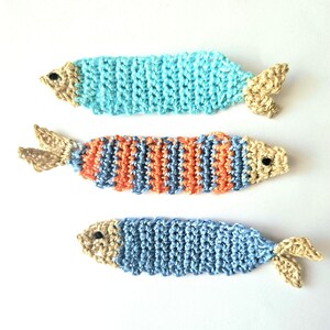 May include: Three crocheted fish ornaments in blue, orange, and light blue with tan fins and eyes.