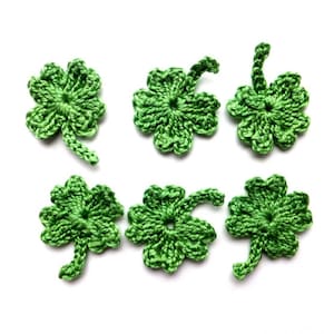 Peut inclure: Huit breloques en forme de trèfle à quatre feuilles en crochet vert. Les breloques sont réalisées avec un fil doux et texturé et ont un aspect délicat et fait main.