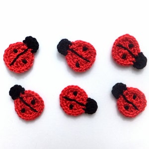 Puede incluir: Seis aplicaciones de mariquita de ganchillo en rojo con manchas negras y cabezas negras.