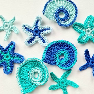 May include: A collection of crocheted sea-themed ornaments in shades of blue and turquoise. The ornaments include starfish, seashells, and a spiral design.