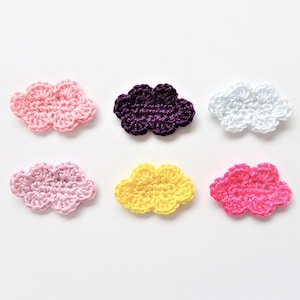 May include: Six crocheted cloud shapes in different colours: pink, purple, white, light pink, yellow, and hot pink.